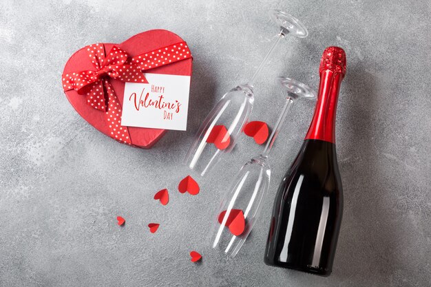 Valentijnsdag kaart met een fles champagne, glazen met een doos chocolaatjes in de vorm van een hart.