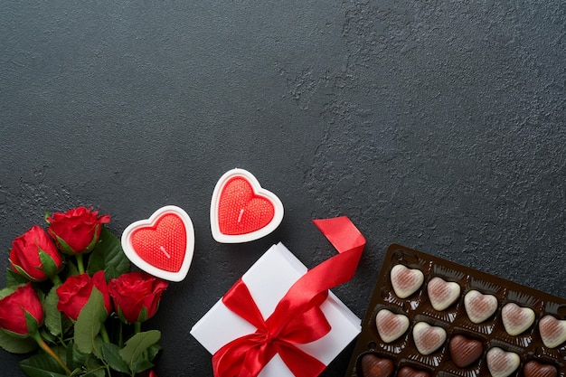 Valentijnsdag kaart Rose rode bloemen brownie koekjes en chocoladesuikergoed op hartvormige geschenkdoos met wijn op zwarte achtergrond Moederdag of Vrouwendag wenskaart Bovenaanzicht plat leggen