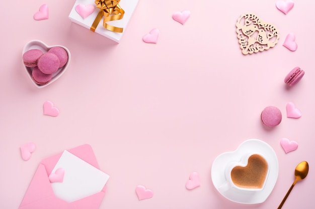 Valentijnsdag kaart. Roze lege envelop, macaron macaroon cookie en hartvormige koffiekopje op roze achtergrond. 8 maart, Womens Mothers Valentijnsdag, verjaardag. Plat lag, bovenaanzicht, kopieer ruimte.