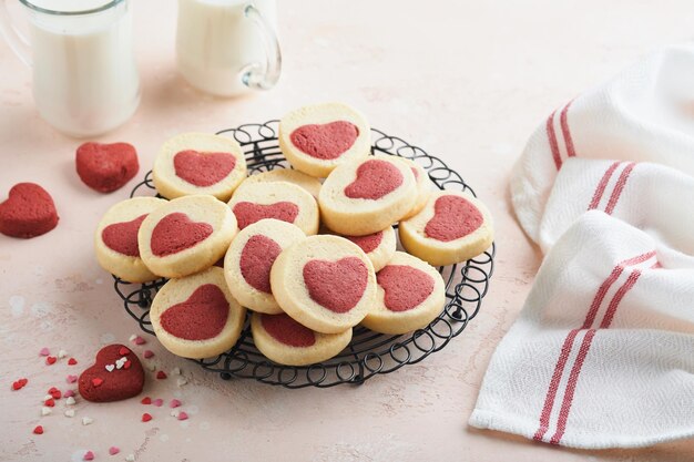 Valentijnsdag koekjes Zandkoekkoekjes in een zoet rood hart op roze plaat op roze achtergrond Moederdag Vrouwendag Zoete feestdagen bakken Bovenaanzicht