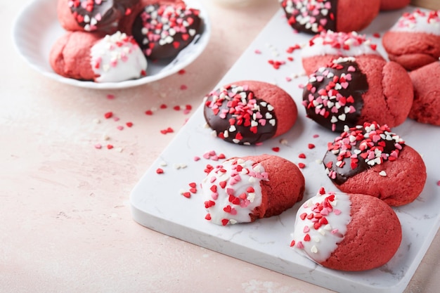 Valentijnsdag koekjes Zandkoekkoekjes met glazuur witte en pure chocolade en hagelslag op bord op roze achtergrond Moederdag Damesdag Zoete feestdagen bakken Bovenaanzicht