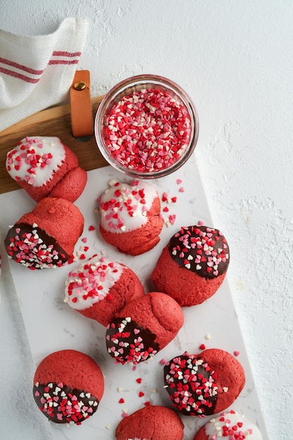 Valentijnsdag koekjes Zandkoekkoekjes met glazuur witte en pure chocolade en hagelslag op bord op witte achtergrond Moederdag Damesdag Zoete feestdagen bakken Bovenaanzicht
