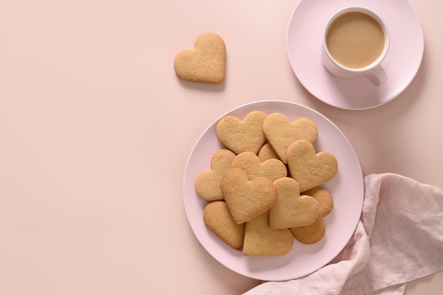Valentijnsdag koffie met melk en hartvormige koekjes op roze plaat.