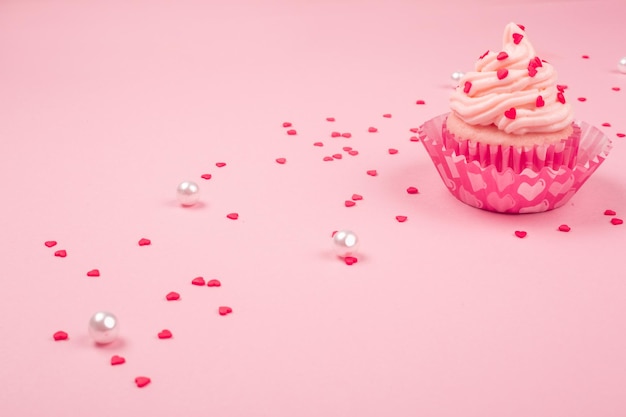 Valentijnsdag liefde cupcake versierd met room en harten op roze achtergrond met kopie ruimte voor tekst