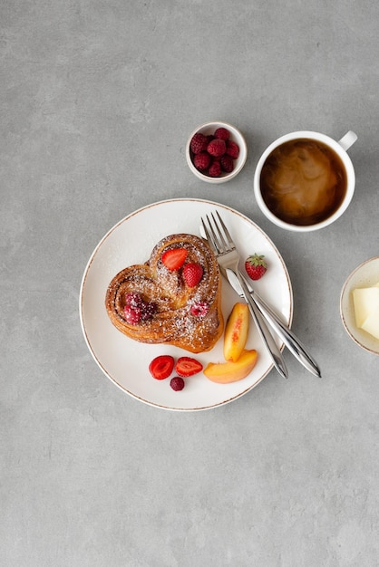 Valentijnsdag ontbijt op grijze achtergrond Broodje met boter en bessen op een witte plaat