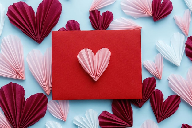 Valentijnsdag plat lag Stijlvolle rode envelop met roze en rode harten samenstelling op blauwe papieren achtergrond Creatieve moderne valentijnsharten uitsparingen Liefdesbrief Happy Valentine's day