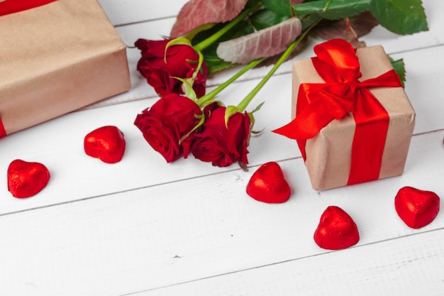 Valentijnsdag. Rode rozen en geschenkdoos op houten tafel