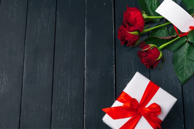 Valentijnsdag. Rode rozen en geschenkdoos op houten tafel