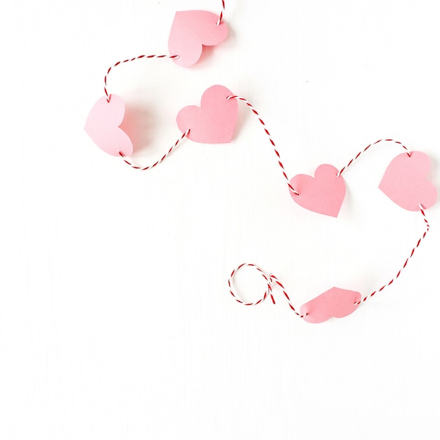 Valentijnsdag samenstelling. Hartsymbool gemaakt van roze papier met touw op wit oppervlak. Plat lag, bovenaanzicht