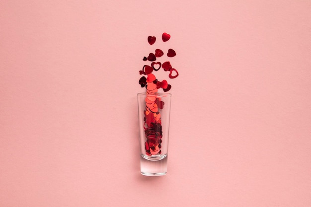 Valentijnsdag shots borrelglas met hart confetti op pastel roze achtergrond