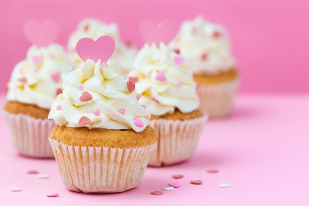 Valentijnsdag snoep. Cupcakes verfraaide harten op een roze achtergrond