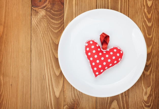 Valentijnsdag speelgoed hart over plaat. Op houten tafel achtergrond met kopie ruimte