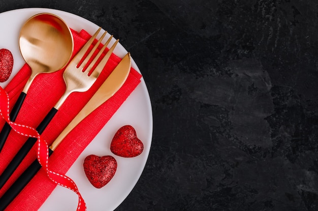 Foto valentijnsdag tafelschikking met gouden mes vork lepel rood lint en harten