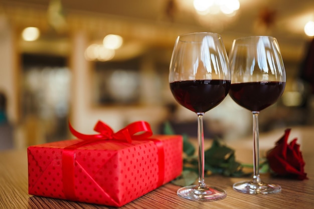 Valentijnsdag viering concept Twee glazen wijn rode roos rode geschenkdoos op houten tafel