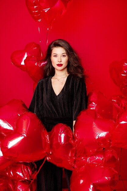 Valentijnsdag vrouw in zwart met rode hartvormige ballonnen plezier