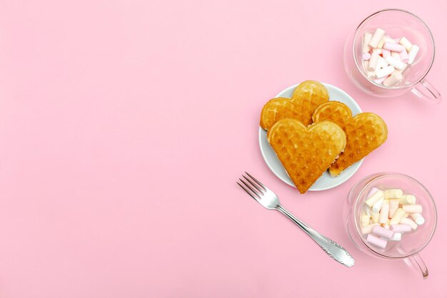 Valentijnsdag Vrouwendag concept tafelschikking met zelfgemaakte Belgische wafels hartvormig op plaat met zoete mini confetti hagelslag kopje koffie bovenaanzicht liefde romantiek achtergrond kopie ruimte