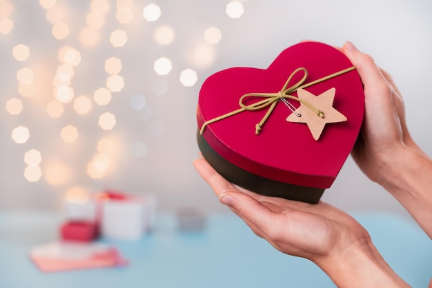 Valentijnsdaggeschenken in hartvormige doos in handen bokeh