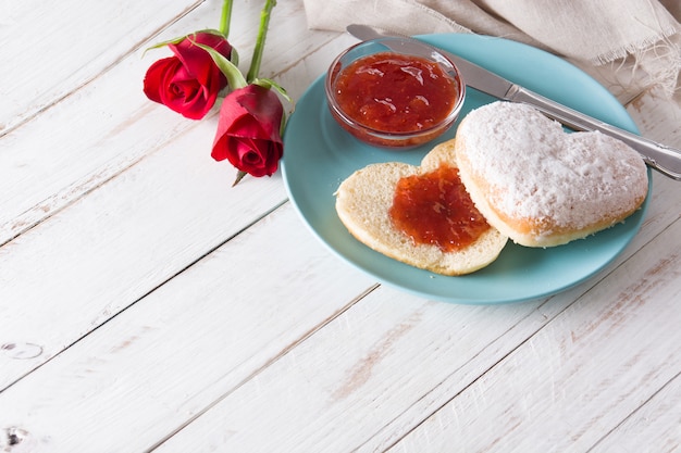 Valentijnsdagontbijt met koffie, hartvormig broodje, bessenjam en rozen