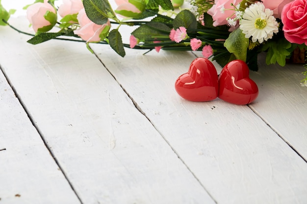 バレンタインデーのロマンチックな赤いハートと白い木製のテーブルにカラフルな花の花束