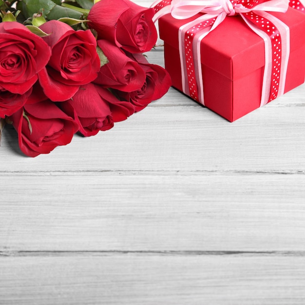 Foto priorità bassa del biglietto di s. valentino del contenitore di regalo e delle rose rosse su legno bianco