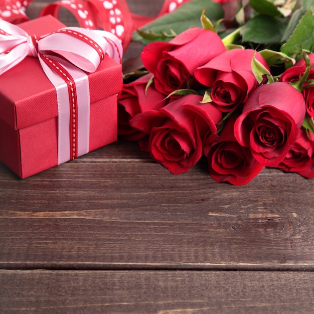 Valentine background of gift box and red roses on wood