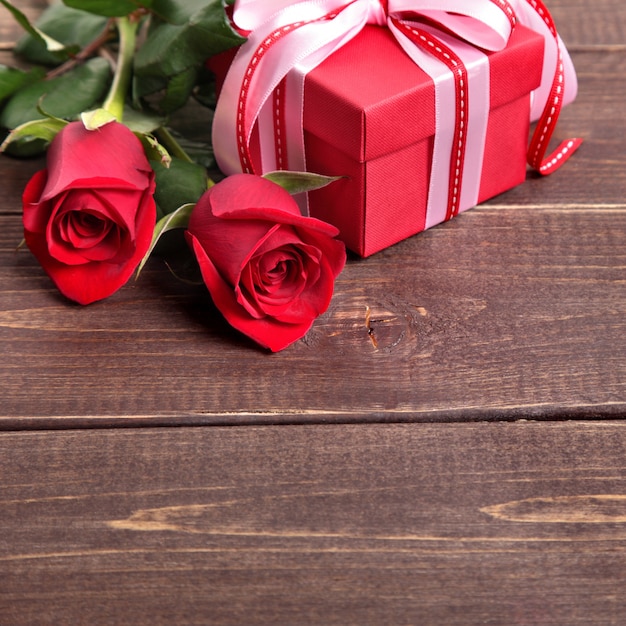 Foto fondo del biglietto di s. valentino del contenitore di regalo e rose rosse su legno