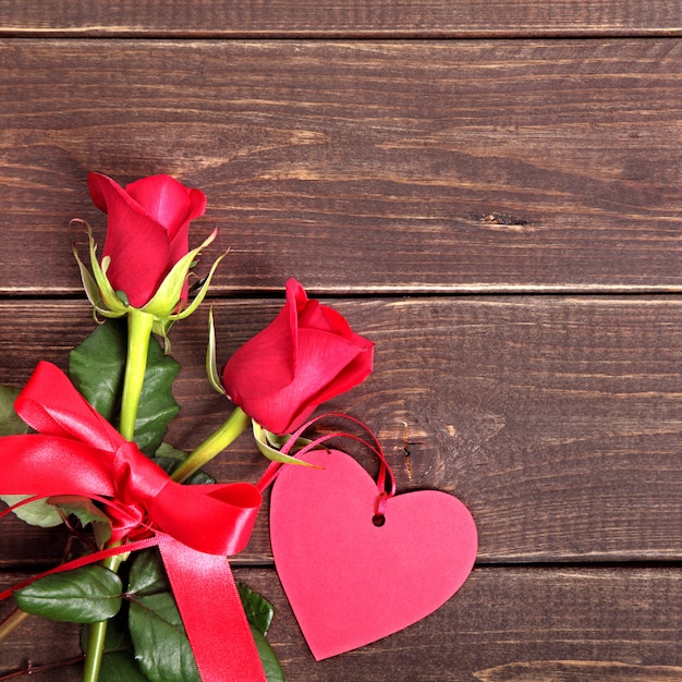 Valentine background of gift tag and red roses on wood