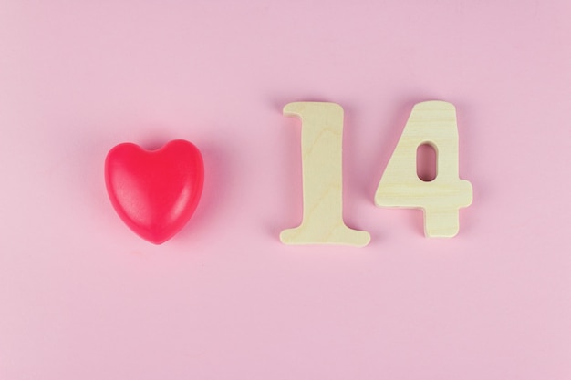 Photo valentine concept. wooden calendar with date 14 february and red heart on pink background.