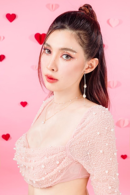 Valentine concept Young Asian sexy woman gathered in ponytail with natural makeup on face have plump lips and clean fresh skin on pink heart pattern background