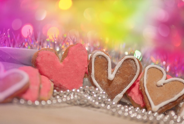 Печенье Валентина в форме сердца Печенье розового сердца на фоне красной ткани Красочное печенье Валентина в форме сердца