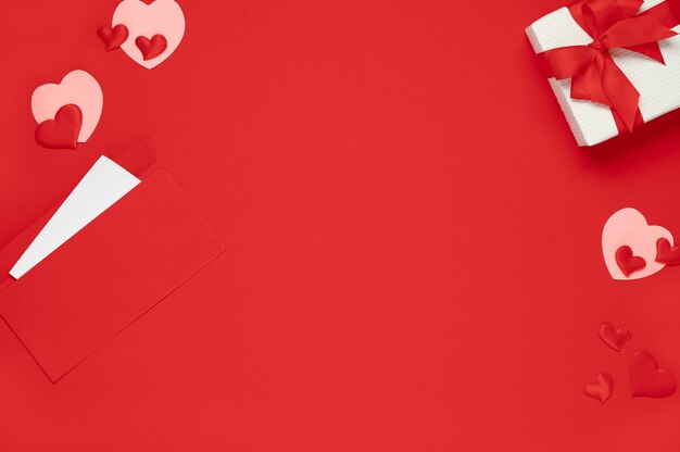 Valentine day background. Top view of gift box and hearts of red background. Flat lay