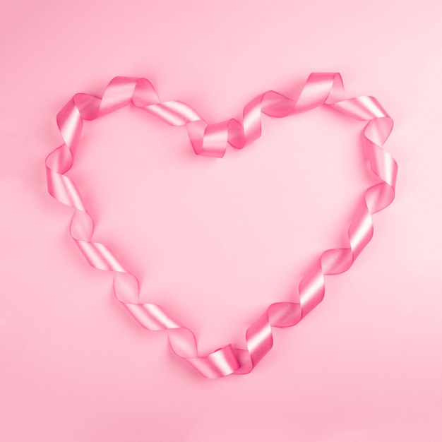Foto sfondo di san valentino con nastro di raso ricci rosa a forma di cuore su carta con spazio per la copia del testo