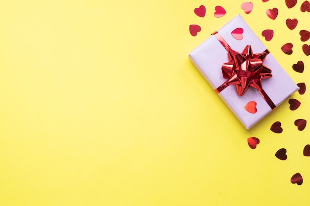 Valentine day composition, Greeting gift box with confetti hearts on yellow background. Flat lay.