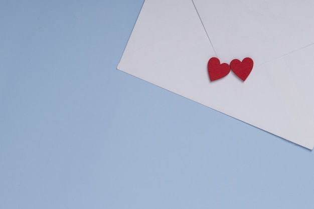 Valentine day greeting concept. Envelope and two red hearts on blue background . Gift, message for lover.