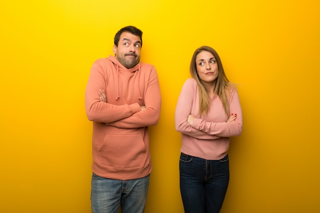 In valentine day Group of two people on yellow background making doubts gesture while lifting the shoulders