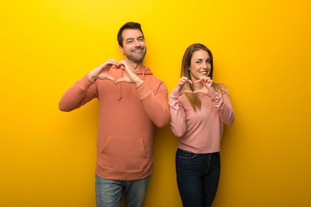 In valentine day Group of two people on yellow background making heart symbol by hands