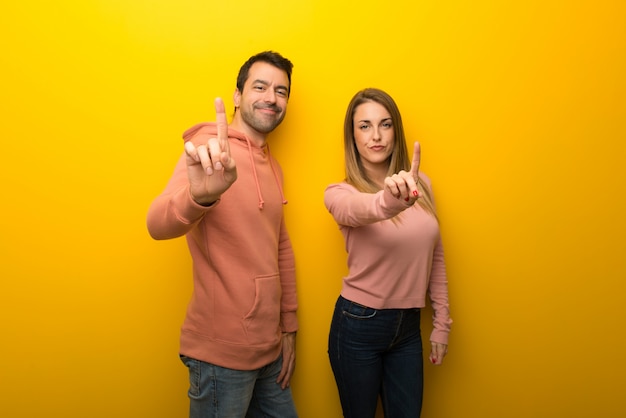 In valentine day Group of two people on yellow background showing and lifting a finger