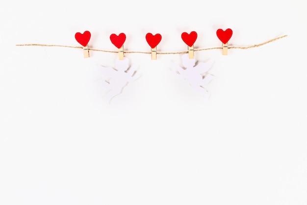 Photo valentine day layout. red hearts and white cupids on wooden clothespins jute twine