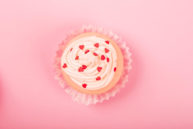 Foto cupcake d'amore di san valentino decorato con crema e cuori su sfondo rosa con spazio per la copia per la vista dall'alto del testo