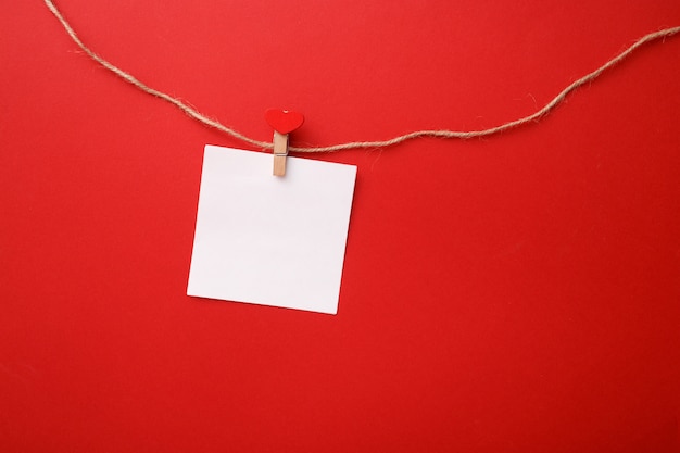 Photo valentine day minimalistic composition. paper note on a clothespin with a heart on a rope. top view, mock up.