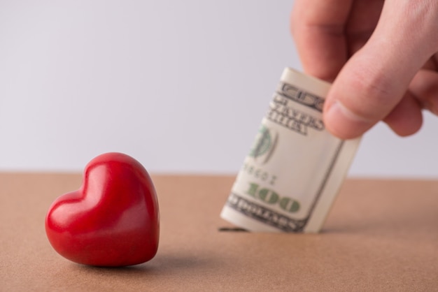 Valentine day wedding profit earnings payment. Cropped closeup photo of man male hand putting banknote into hole