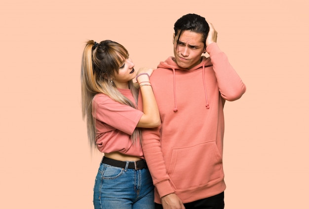 In valentine day Young couple having doubts while scratching head over pink background