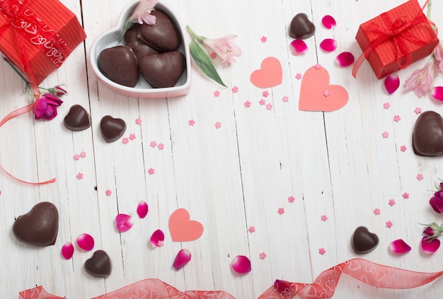 Valentine gift box and red heart shapes on white wooden board