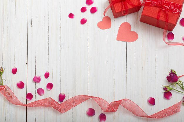 Valentine gift box and red heart shapes on wooden board