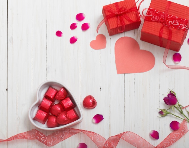 Valentine-giftdoos en rode hartvormen op witte houten raad