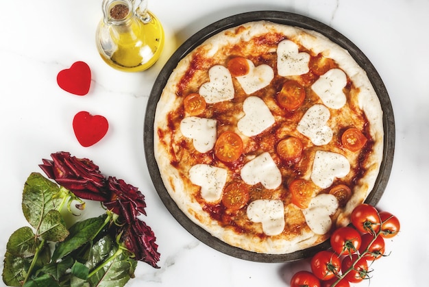 Valentine holiday food , pizza margarita with heart shaped cheese, white marble , copyspace top view, with roses