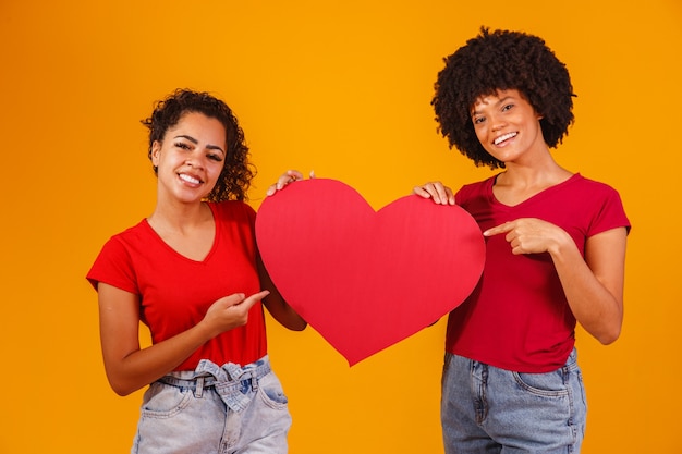 Valentine lesbian couple holding a paper heart. valentine's day concept