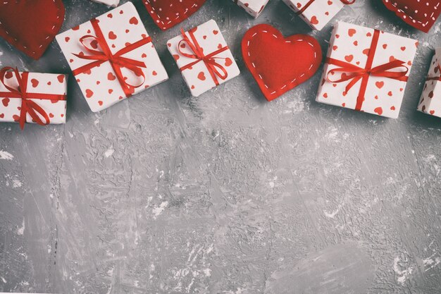Валентина или другой праздничный подарок ручной работы в бумаге с красным сердцем и подарочной коробке в праздничной обертке. Подарочная коробка подарка на серый цемент столешницы с копией пространства, пустое пространство для дизайна