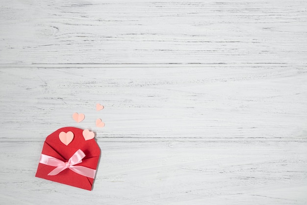 Photo valentine red envelope with pink hearts. valentines day card, love flat lay on white wooden background with copy space.