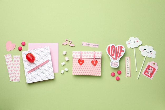 Valentine's Day accessories on green background, top view